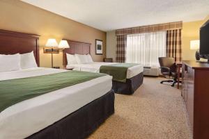 una camera d'albergo con due letti e una televisione di Country Inn & Suites by Radisson, Stevens Point, WI a Stevens Point