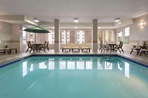 una grande piscina con sedie e tavoli in una camera d'albergo di Country Inn & Suites by Radisson, Stevens Point, WI a Stevens Point