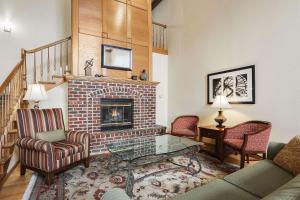 Country Inn & Suites by Radisson, Green Bay, WI في اشوبينون: غرفة معيشة بها موقد وأريكة وكراسي