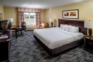 Country Inn & Suites by Radisson, Princeton, WV في برنستون: غرفة الفندق بسرير كبير ومكتب