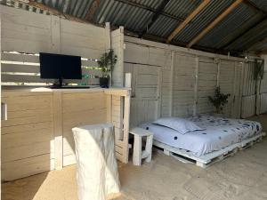a bedroom with a bed and a desk with a television at “SandSerenity EcoHostal Punta Arena” in Cartagena de Indias