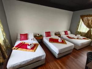 Zimmer mit 3 Betten mit roter und weißer Bettwäsche in der Unterkunft 1 Hati Homestay Sepang in Sepang