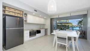 una cucina con frigorifero in acciaio inossidabile e tavolo con sedie di Beachfront - Nelly Bay Apartment a Nelly Bay