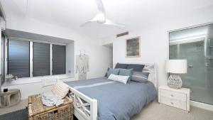a white bedroom with a bed and a window at Beachfront - Nelly Bay Apartment in Nelly Bay
