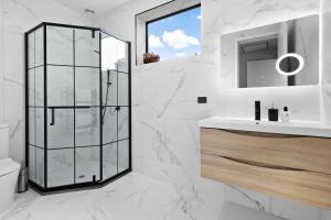 a white bathroom with a shower and a sink at The Headley Loft in Queenstown
