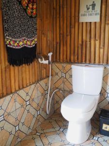 ein weißes WC im Bad mit einem Rohr in der Unterkunft Tetebatu Hostel in Tetebatu
