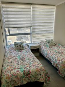 a bedroom with two beds and a window with blinds at Departamento de dos dormitorios en La Serena in La Serena