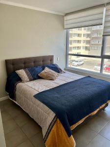a bed in a room with a large window at Departamento de dos dormitorios en La Serena in La Serena