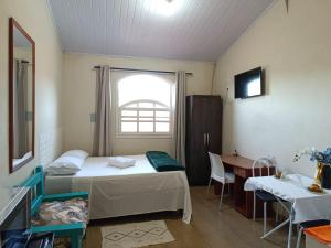 a room with two beds and a table and a window at Recanto Vila Rica Mariana in Mariana