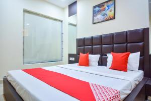 a bedroom with a large bed with red pillows at OYO Kings Inn in Ludhiana