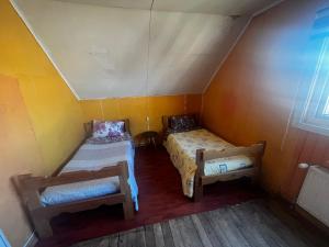 an attic room with two beds and a window at Cabañas 644 in Porvenir