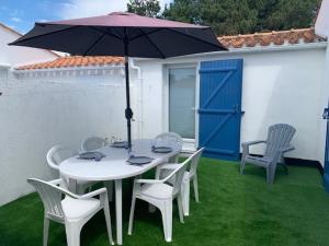 ein weißer Tisch und Stühle mit einem Regenschirm auf dem Gras in der Unterkunft Maison Bretignolles-sur-Mer, 3 pièces, 4 personnes - FR-1-231-300 in Brétignolles-sur-Mer