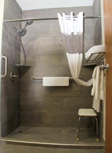 y baño con ducha con cortina de ducha y silla. en Super 8 by Wyndham Oskaloosa IA, en Oskaloosa