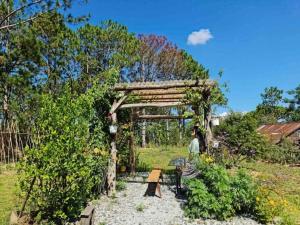 a woman walking through a wooden arch in a garden at Family house - stay on pine hill Dalat in Xuan An