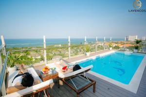 two people laying on chairs next to a swimming pool at Lavencos Hotel Da Nang in Da Nang