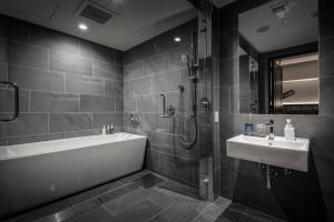 a bathroom with a bath tub and a sink at Nest Hotel Osaka Umeda in Osaka