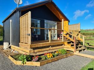 a tiny house with a porch and flowers at Franvannah Cabin in Waihi