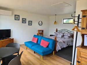 1 dormitorio con 1 cama y 1 silla azul en Franvannah Cabin, en Waihi