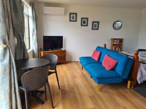 sala de estar con sofá azul y mesa en Franvannah Cabin, en Waihi