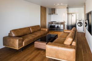 a living room with two brown couches and a kitchen at Hotel Dios - Vacation STAY 31239v in Awaji