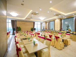 un ristorante con tavoli in legno e sedie rosse di Lavencos Hotel Da Nang a Da Nang