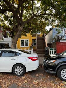 two cars parked in front of a yellow house at Bumblebee House in Oakland