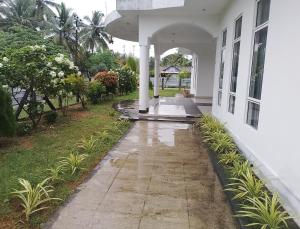 a porch of a house with rain on the sidewalk at Laxsume Guest House Nilaveli in Nilaveli