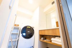 uma casa de banho com uma máquina de lavar roupa e um espelho. em ＳＯ Ｋｙｏｔｏ Ｆｕｓｈｉｍｉ Ｉｎａｒｉ - Vacation STAY 76147v em Quioto