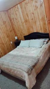 Cama en habitación con pared de madera en Cabaña con tinaja, en Lanco