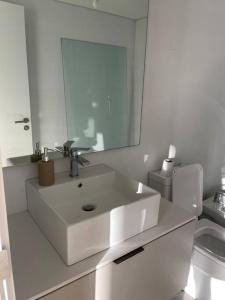 Baño blanco con lavabo y espejo en Apto a estrenar en Punta en Punta del Este