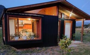 una pequeña casa negra pequeña con una ventana grande en CABAÑAS BRISAS VOLCANICAS, en Cunco