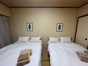 2 camas en una habitación con sábanas blancas y toallas en Sunny Heights Osaki - Vacation STAY 14998, en Tokio