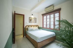 a bedroom with a bed and a window and a plant at House of Comfort - 3 BR & 3 baths - 1' to Hoan Kiem Lake & Old Quarter in Hanoi