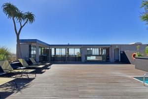 a deck with lounge chairs and a palm tree at Unit 305 Cape Royale Luxury Apartments in Cape Town