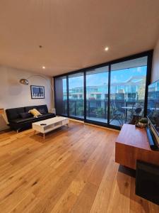 a living room with a couch and large windows at Metro Retreat on Burnley in Melbourne
