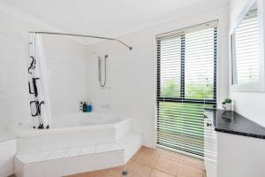 a white bathroom with a tub and a shower at Spacious & Serene! 3Bed/2Bath/2+Cars ~ House in Mount Ommaney