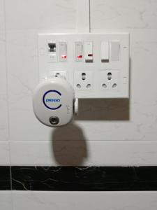 un interrupteur électrique sur un mur à côté d'une prise dans l'établissement Kailasha - Hostel Cum PG, à Mumbai