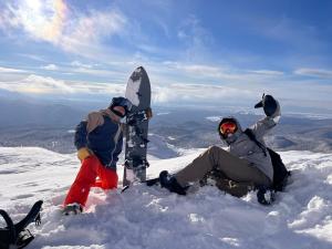 two people sitting in the snow with snowboards on a mountain at TOTONOU Place in Asahikawa