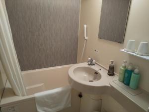 a white bathroom with a sink and a bath tub at Hotel Route-Inn Ashikaga Ekimae in Ashikaga
