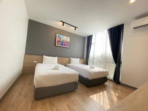 um quarto de hotel com duas camas e uma janela em โรงแรม เดอะโมเดล การ์เด้น em Yasothon