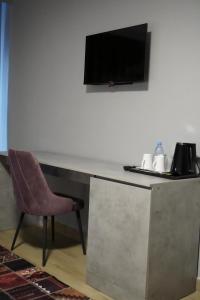 a desk with a chair and a television on a wall at Dami Astana Hotel in Astana