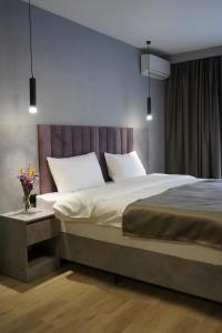 1 dormitorio con 1 cama grande con almohadas blancas en Dami Astana Hotel en Astaná