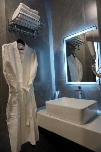 a white robe hanging on a rack next to a sink at Dami Astana Hotel in Astana