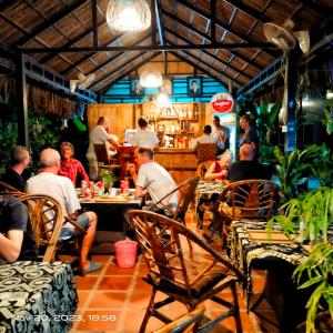 een groep mensen die aan tafel zitten in een restaurant bij The Mango Tree Guesthouse in Kampot