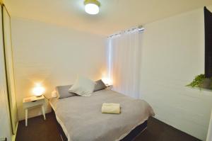 a small bedroom with a bed with a white blanket at Riverview Holiday Apartment 107 - Kalbarri WA in Kalbarri