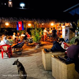 een hond voor een restaurant met mensen bij The Mango Tree Guesthouse in Kampot