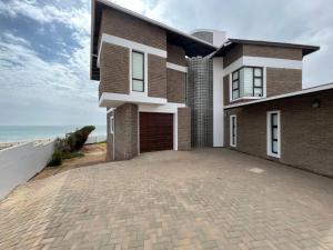 a house with a driveway in front of the ocean at Beach House in Hentiesbaai