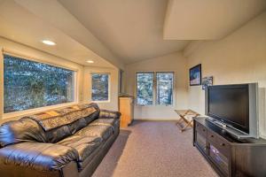 a living room with a leather couch and a flat screen tv at Swanhouse. Waterfront home. in Seldovia