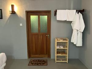 ein Badezimmer mit einer Holztür und weißen Handtüchern in der Unterkunft Kingfisher Beach Resort -Yala in Kirinda
