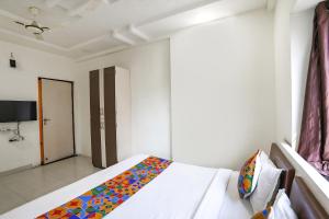 a bedroom with a bed with a colorful blanket on it at FabHotel HRG Destiny in Nagpur